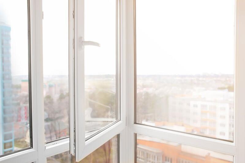 Geöffnetes weißes Kunststofffenster in einer modernen Wohnung mit Blick auf eine städtische Umgebung bei Tageslicht.