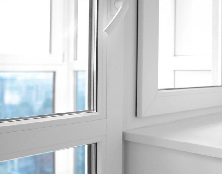 Nahaufnahme eines geöffneten weißen Kunststofffensters mit Doppelverglasung in einem modernen, hellen Raum.